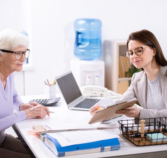 senior-elegant-woman-looking-at-insurance-form-held-by-young-female-agent.jpg